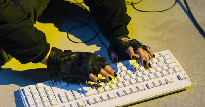 A Person Wearing Black Gloves Typing on the White Keyboard