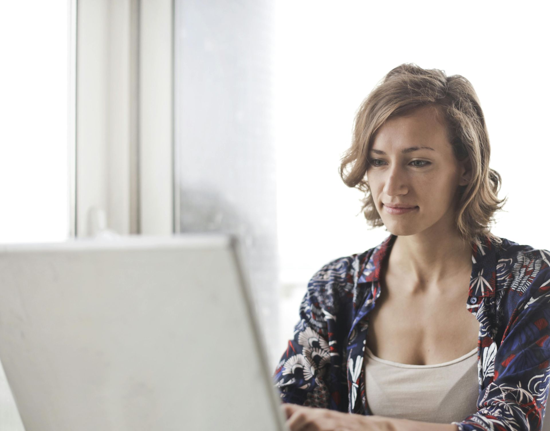 Woman in Blue Floral Top Sitting While Using Laptop